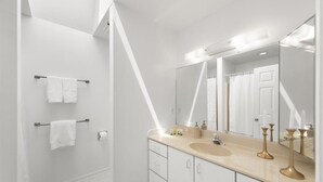 A modern bathroom with a large mirror, a sink, and a shower area. - Serene Sunrise & Shimmering Skyline. 5 Star Hosts (Ocean City)
