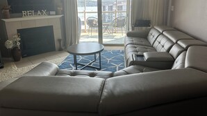 Un soggiorno moderno con un divano componibile, una TV a schermo piatto, un camino e vista su un balcone con mobili da esterno.