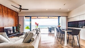 Una sala de estar moderna con sofá, televisión y vista al océano.