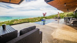 Un patio moderno al aire libre con piscina, zona de estar y vistas al océano.