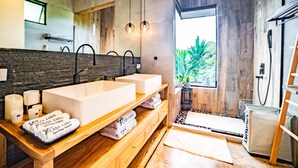 Un baño moderno con dos lavamanos, un tocador de madera, velas y una zona de ducha.