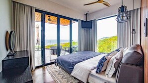 Un dormitorio con una cama grande, televisor y vista al océano.
