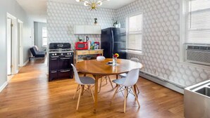 A modern kitchen with a wooden dining table, white chairs, a black refrigerator, and a red microwave. - 5⭐️BEST PRICE⭐️ Whole apt.3 bdrm for 2-8, long term (Providence)
