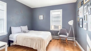 A bedroom with a bed, a chair, a floor lamp, and a wall with framed pictures. - 5⭐️BEST PRICE⭐️ Whole apt.3 bdrm for 2-8, long term (Providence)