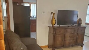 A living room with a dark brown sofa, a wooden cabinet with a flat-screen TV, and a vase on top. - 5⭐️BEST PRICE⭐️Robert's 3 Room for 2-7ppl Long term (Providence)