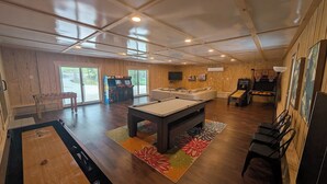 Amplio espacio interior con mesa de billar, mesa de fútbol de mesa y televisor montado en la pared.