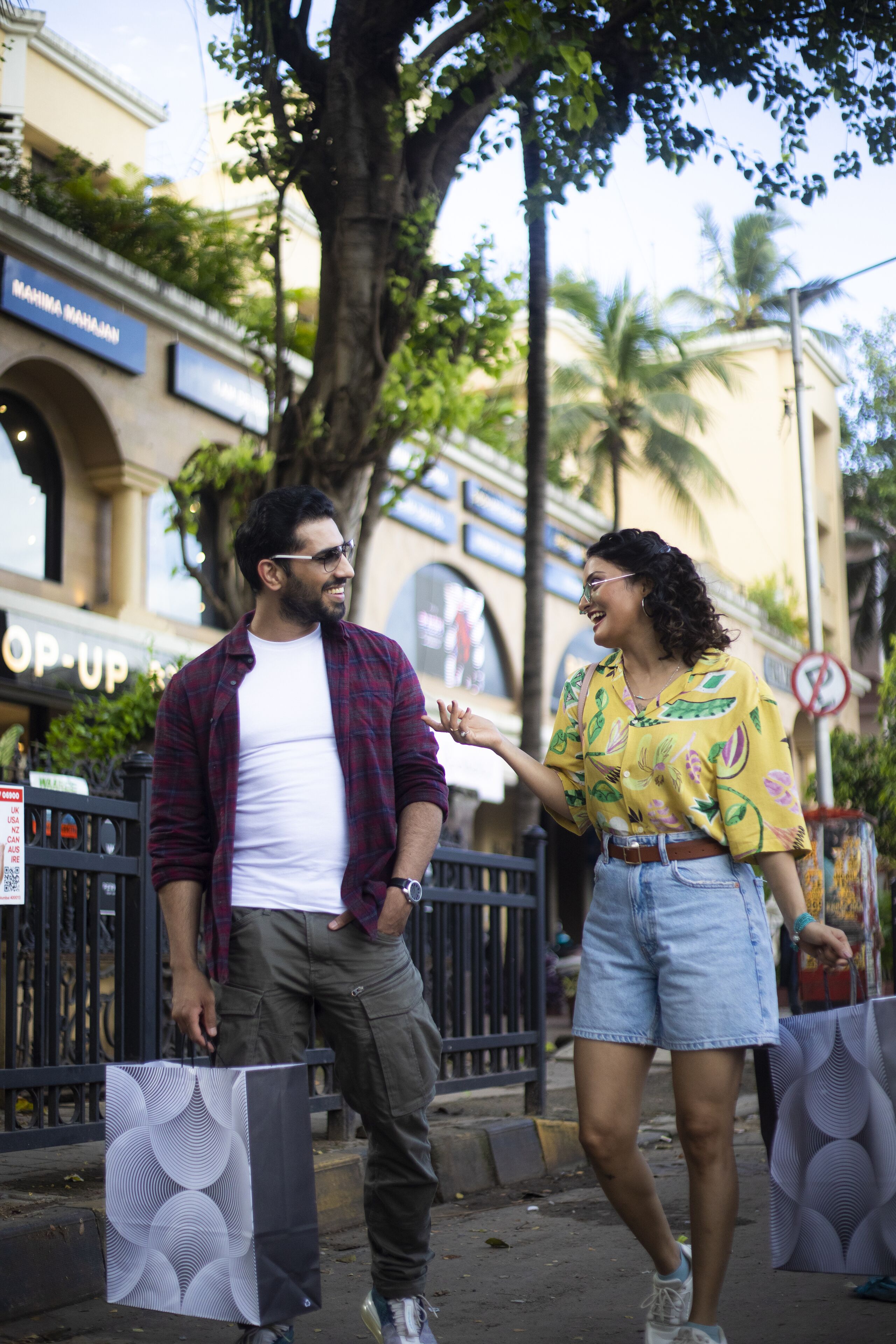 Un hombre y una mujer caminando por la acera, llevando bolsas de compras.