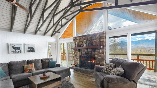 A spacious living room with a stone fireplace, a large sofa, and a comfortable seating area. - Ski Chalet: 0.5 mi to slopes. Great view-Fireplace-central A/C (Sugar Mountain)