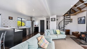 A modern living space with a kitchen, a light blue sofa, a staircase, and a fireplace. - Sparkling 3-bedroom home with fireplace and views (National Park)