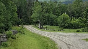 A dirt road winding through a forest with a mountain in the background. - Cozy Mountain View Retreat (Brighton)