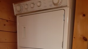 A stacked washer and dryer unit in a wooden room. - Cozy Mountain View Retreat (Brighton)