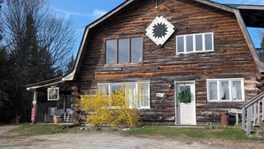 Ein rustikales Holzhaus mit einem großen Fenster, einer Tür mit einem Kranz und einem markanten Sternenmusterfenster.