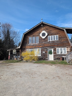 A rustic wooden building with a large window, a door with a wreath, and a distinctive starburst window design. - Cozy Mountain View Retreat (Brighton)