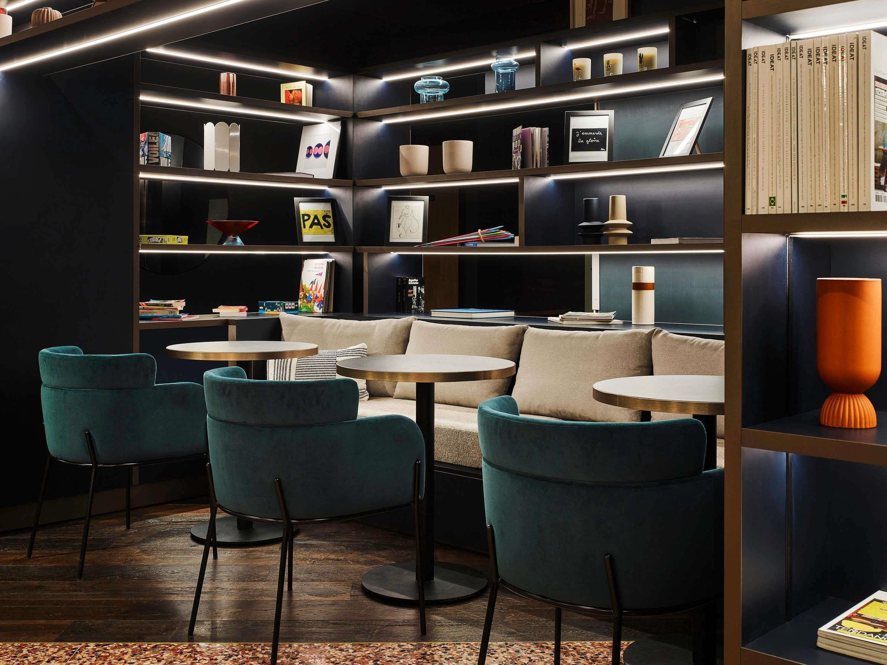 A modern library with bookshelves, a sofa, and round tables.