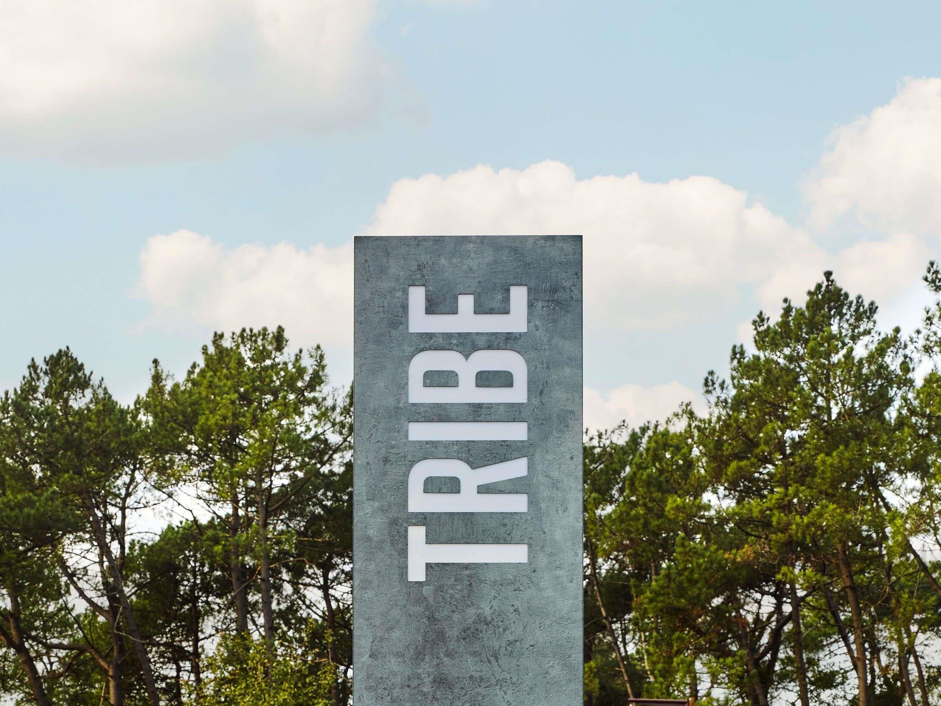 Un letrero vertical con la palabra 'TRIBE' en letras grandes.