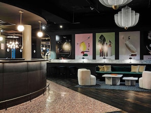 Un bar moderno con barra curva, asientos y arte abstracto en la pared.