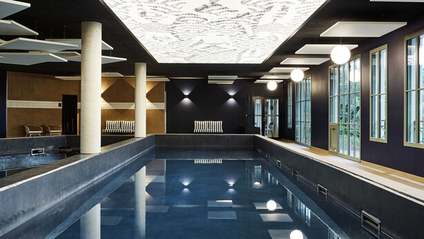 Ein geräumiger Innenpool mit einem gemusterten Boden und einer Decke mit geometrischem Design.