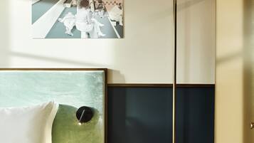 A hotel room with a bed, a headboard, a wall-mounted artwork, a mirror, and a nightstand.