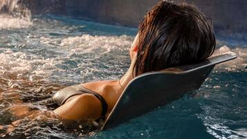 Una persona recostada en un jacuzzi, con agua salpicando.