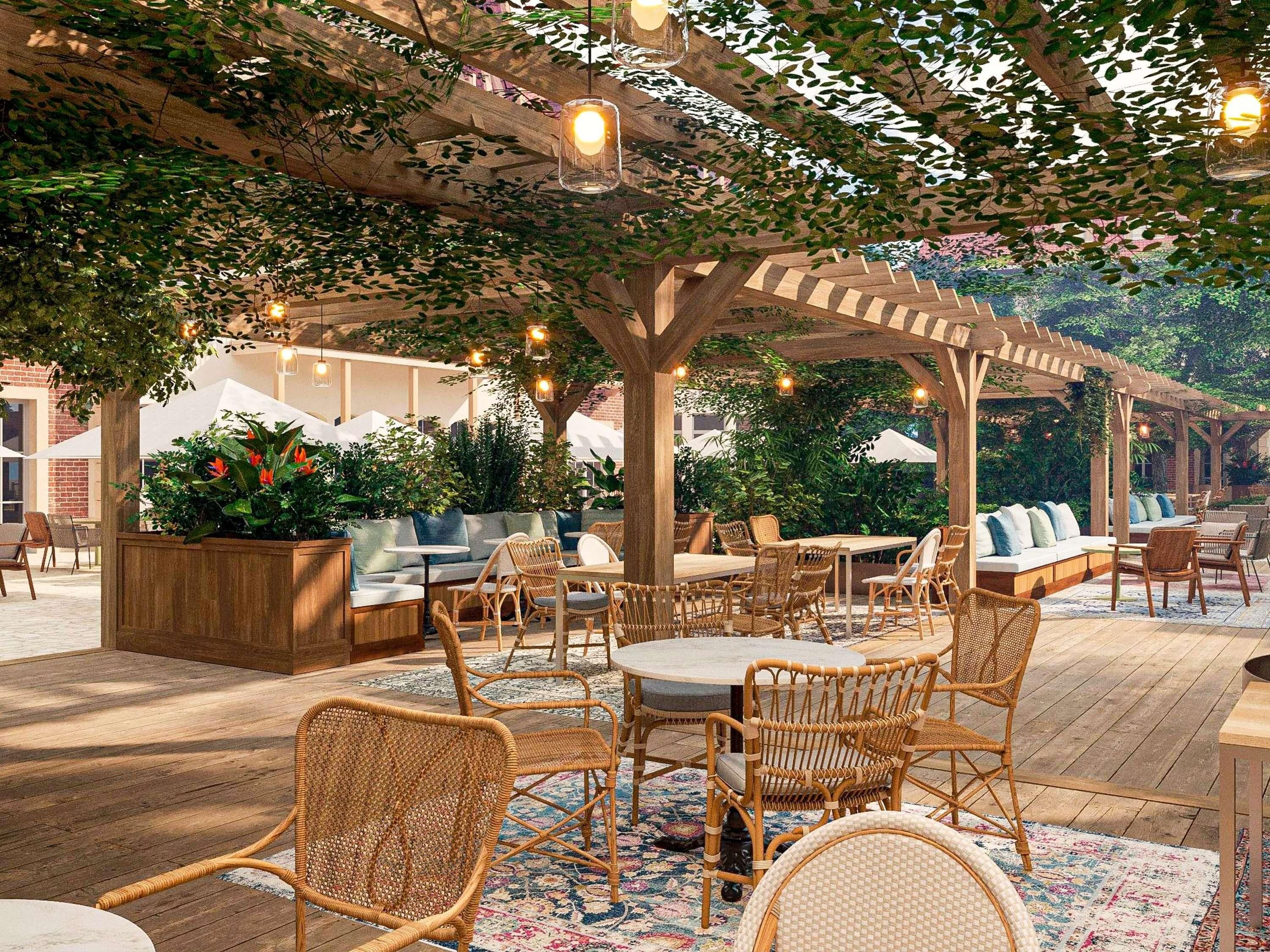 An outdoor patio area with wicker furniture, a wooden pergola, and string lights.