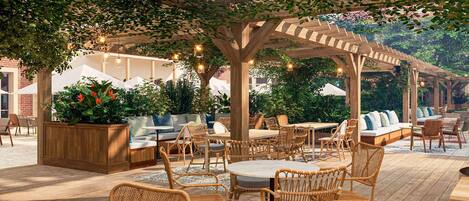 An outdoor patio area with wicker furniture, a wooden pergola, and string lights.