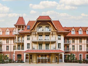 A multi-story building with a red-tiled roof, balconies, and a covered entrance area. - Tribe Le Touquet (Le Touquet-Paris-Plage)