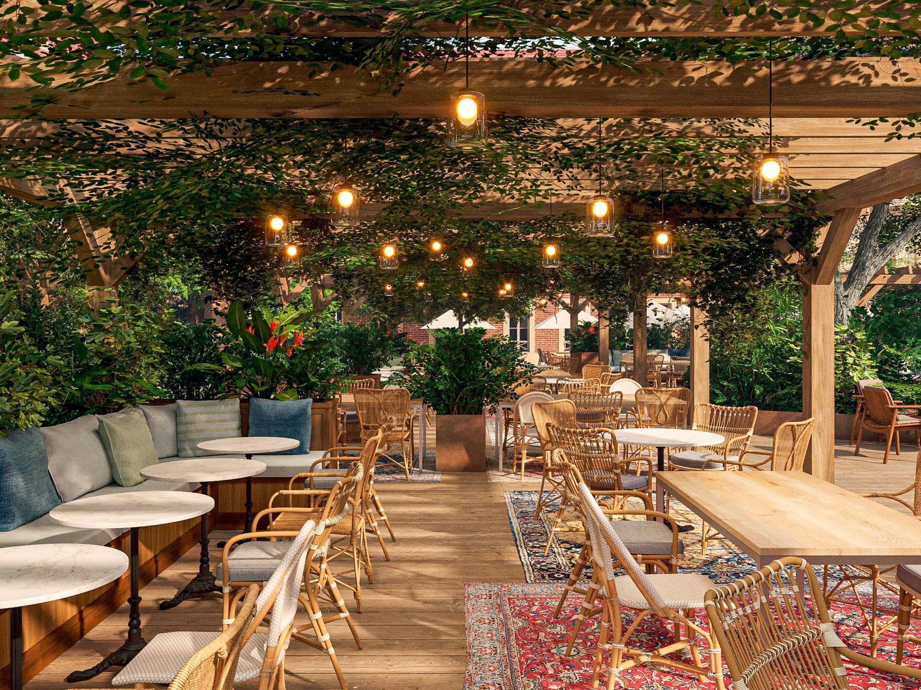Un espace extérieur aménagé pour les repas, avec des meubles en osier, des tables rondes et des lampes suspendues.