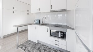 Eine moderne Küche mit weißen Schränken, einer Granit Arbeitsplatte, einem Einbauofen und einem Edelstahlspülbecken.