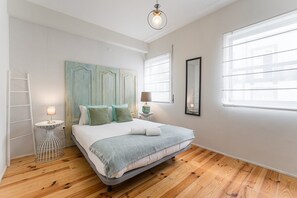 A bedroom with a bed, bedside tables, a ladder, and a large window.