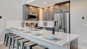A modern kitchen with a large island, stainless steel appliances, and wooden cabinets.