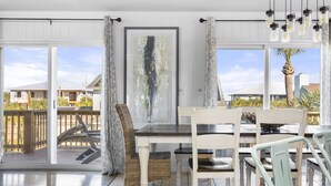 A dining area with a table and chairs, a large abstract painting, and a view of the outside. - Spring Break Ready! Pool | Game Room | Sleeps 21 (Gulf Breeze)