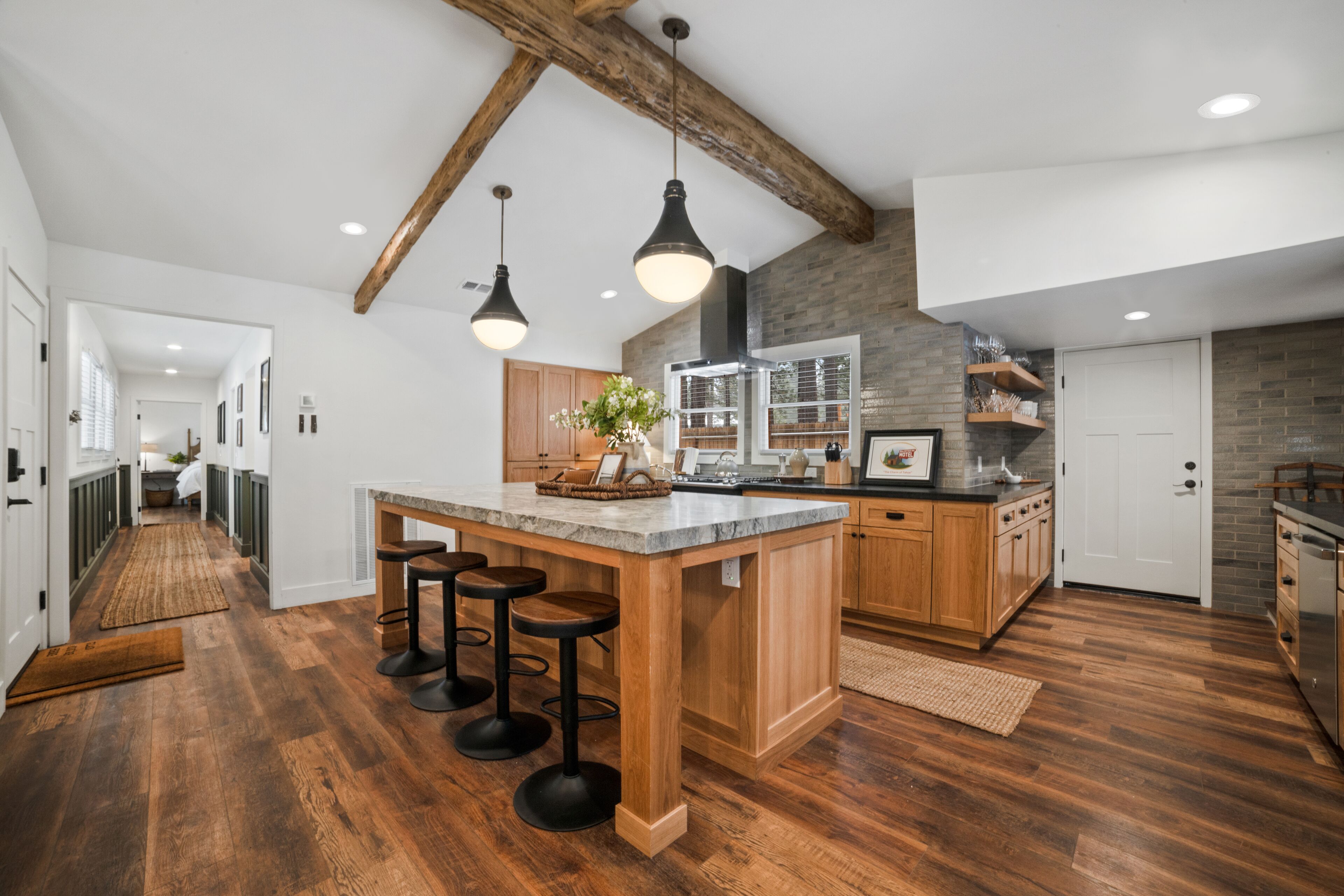 Une cuisine spacieuse dotée d’un grand îlot central, de tabourets de bar en bois et de luminaires suspendus.