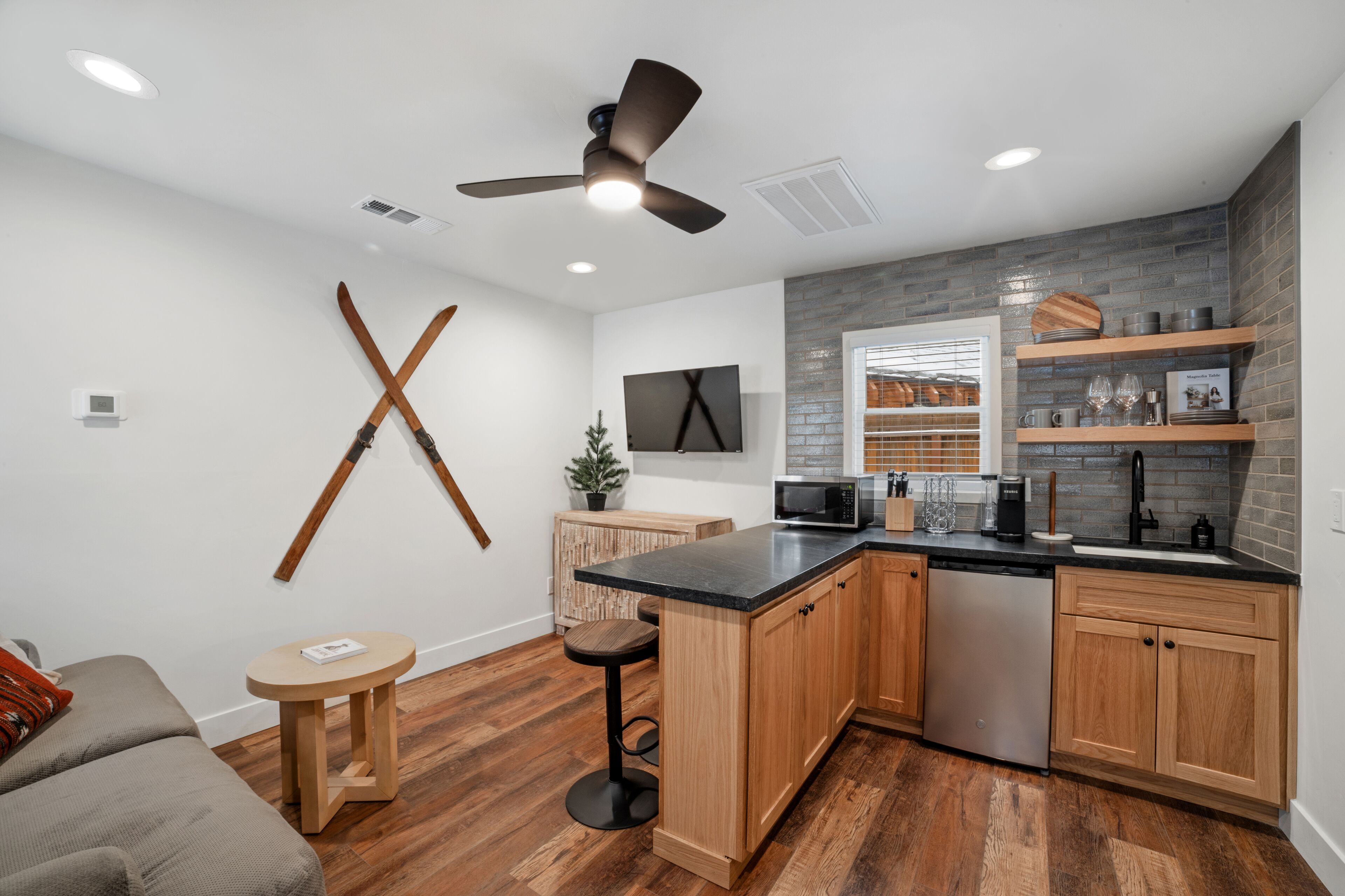 A modern kitchen with wooden cabinets, a black countertop, and a built-in microwave.