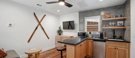 Una cocina moderna con armarios de madera, encimera negra y microondas integrado.