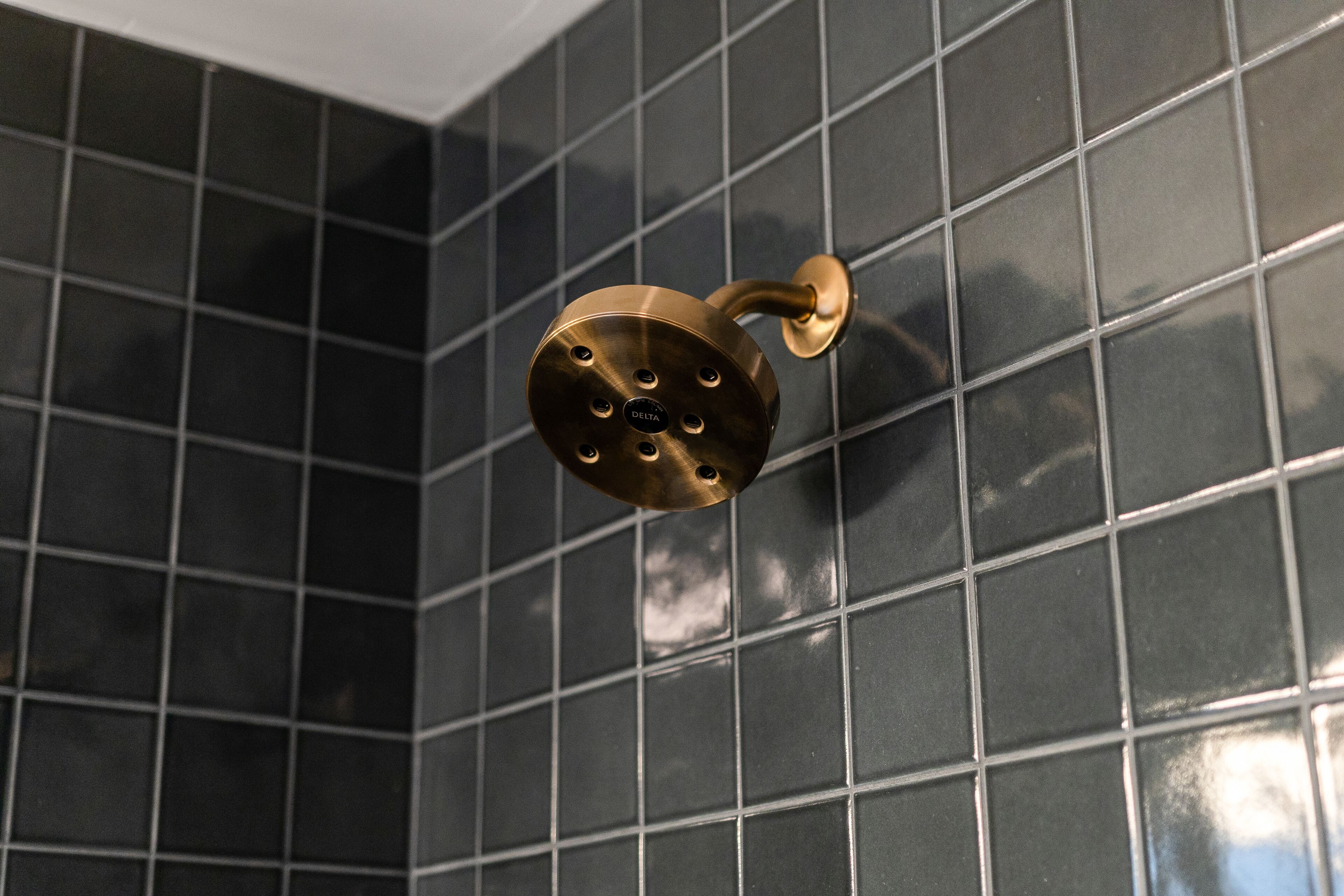 A showerhead mounted on a tiled wall.