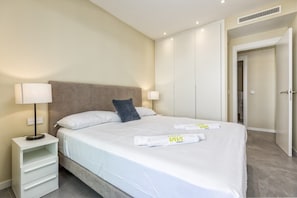 A hotel room with a bed, bedside lamps, a wardrobe, and a bathroom door.
