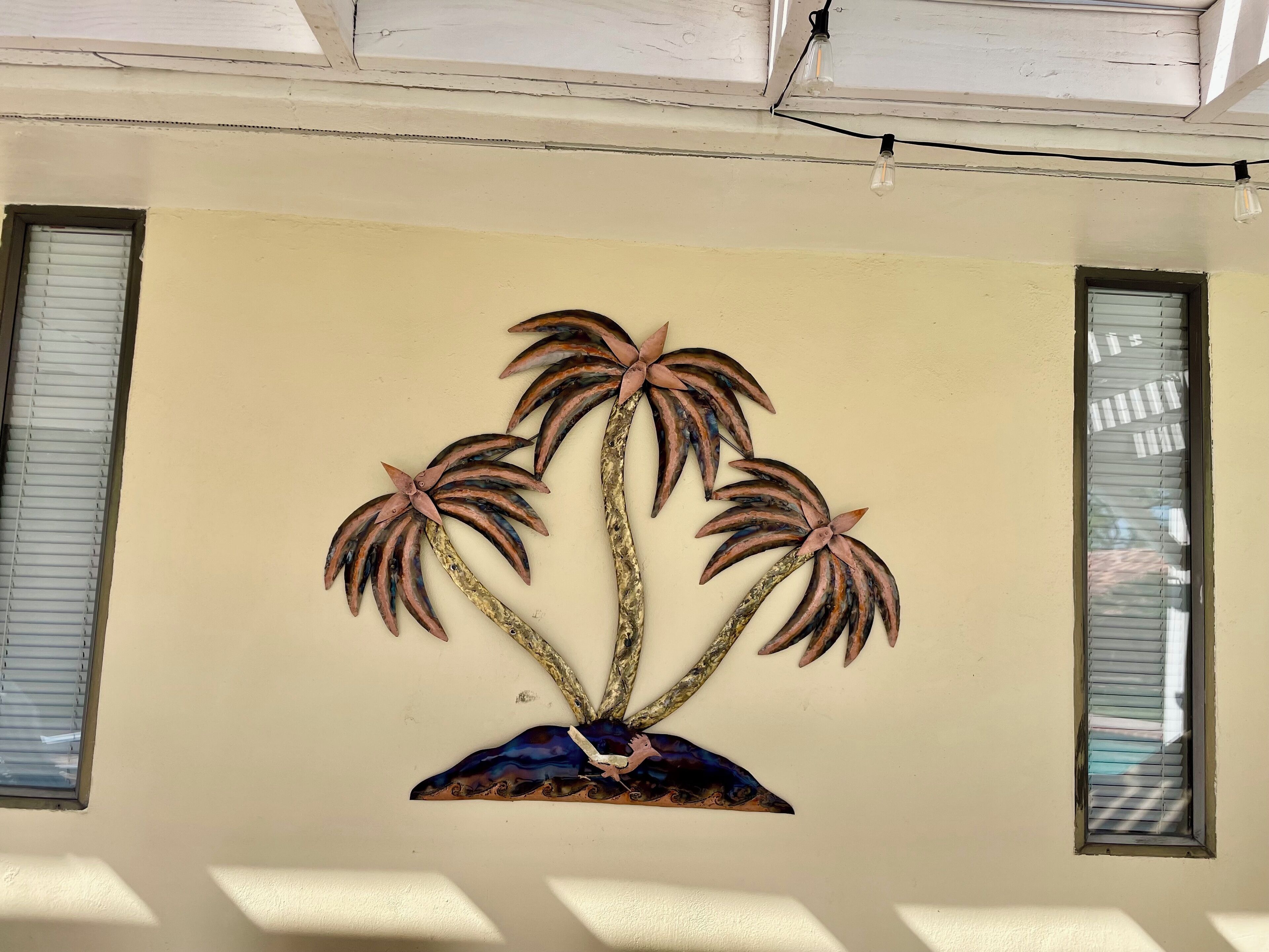 A wall with a decorative metal palm tree sculpture.