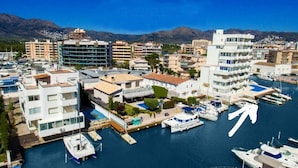 A marina with boats docked, surrounded by multi-story buildings with balconies and terraces.