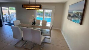 Un comedor moderno con una mesa de vidrio, sillas blancas y una lámpara colgante.
