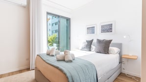 A modern bedroom with a large bed, a bedside table, and a view of the outdoors through a sliding door. - Terrace Apartment by Atlantic Holiday (Funchal)