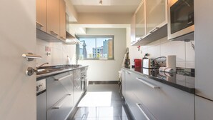 A modern kitchen with stainless steel appliances, a window with a view of buildings, and a tiled floor. - Terrace Apartment by Atlantic Holiday (Funchal)