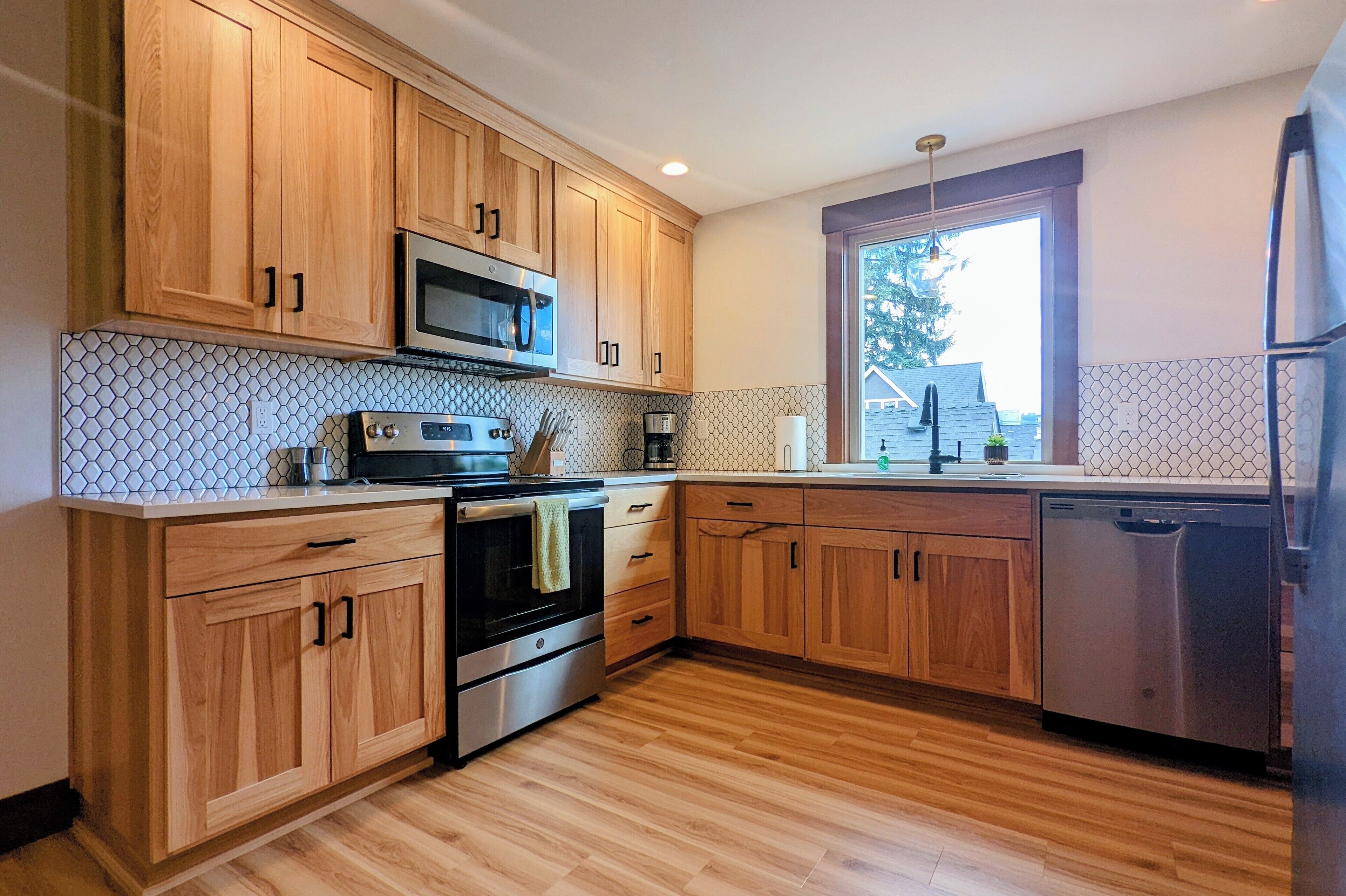 A modern kitchen with wooden cabinets, stainless steel appliances, and a tiled backsplash.