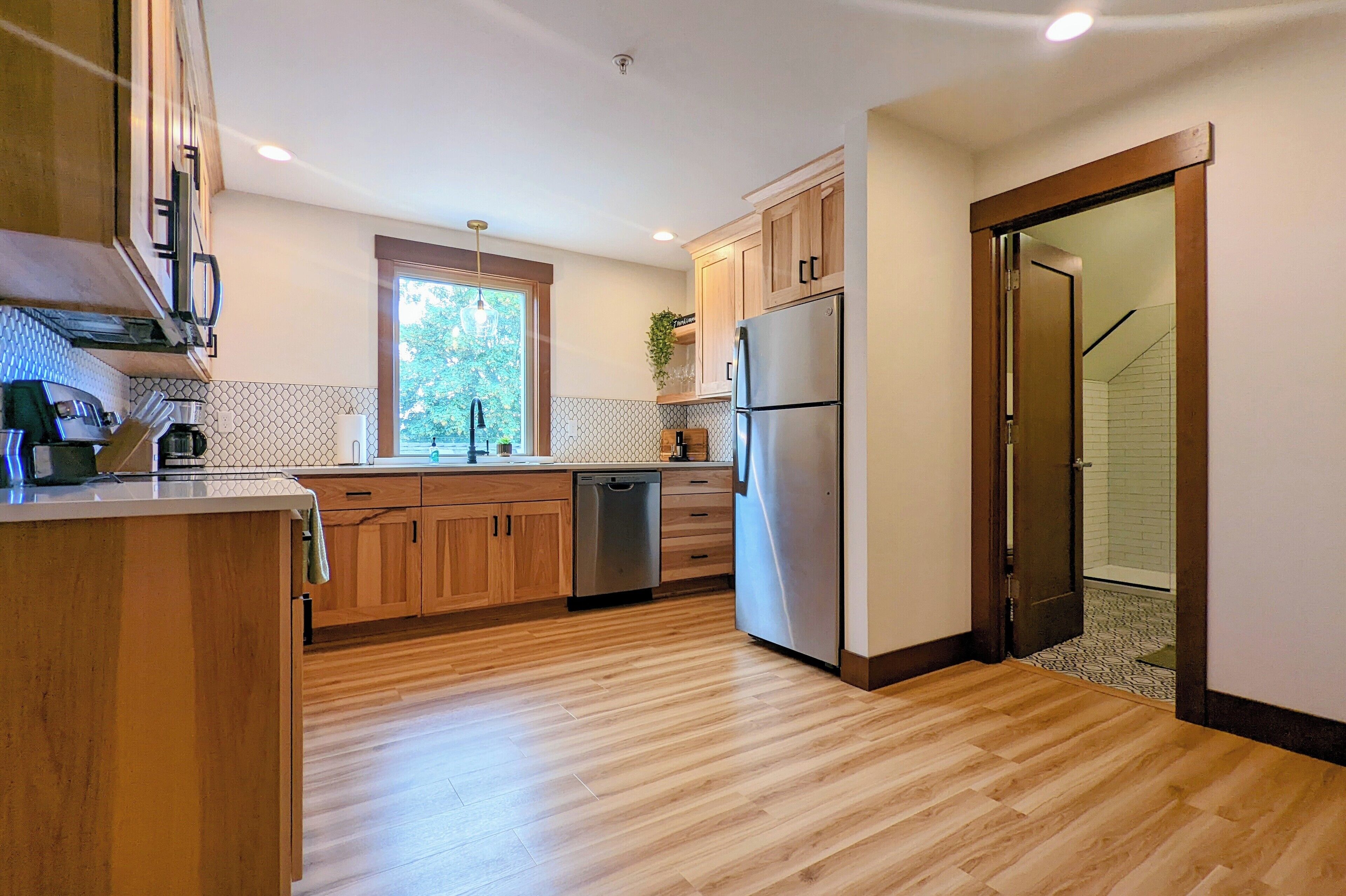 A modern kitchen with wooden cabinets, stainless steel appliances, and a tiled backsplash.