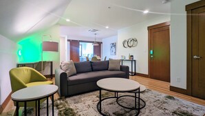 Een moderne woonkamer met een bank, twee ronde tafels en een groene fauteuil.