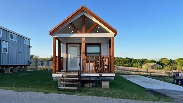 A small, single-story cabin with a wooden deck and a front door, situated on a grassy area with a clear sky. - One bedroom  in United States of America, Hutto (Hutto)