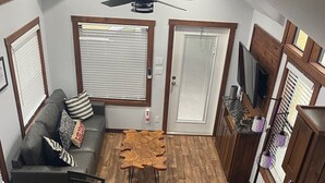 A compact living space with a loft bedroom, a dining area with a round table, and a kitchenette. - One bedroom  in United States of America, Hutto (Hutto)