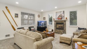 Una sala de estar con chimenea, televisor y dos sofás.