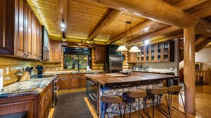 A log cabin kitchen with a central island, stone accents, and wooden cabinetry. - Riverside Luxury Retreat - Hot Tub, Fire Pit, Games & Mesmerizing Views (Payson)