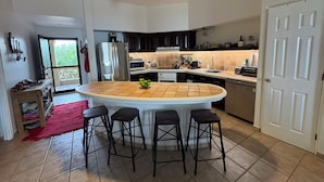 A modern kitchen with a central island, dark cabinets, and a ceiling fan.