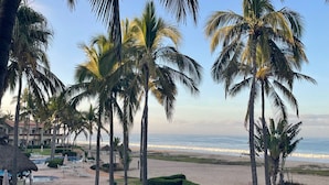 A resort with a pool area, palm trees, and a beach view.